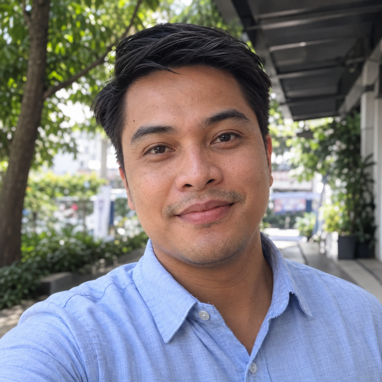 Casual Facebook-style profile photo of a fictional Filipino man in a light-blue shirt