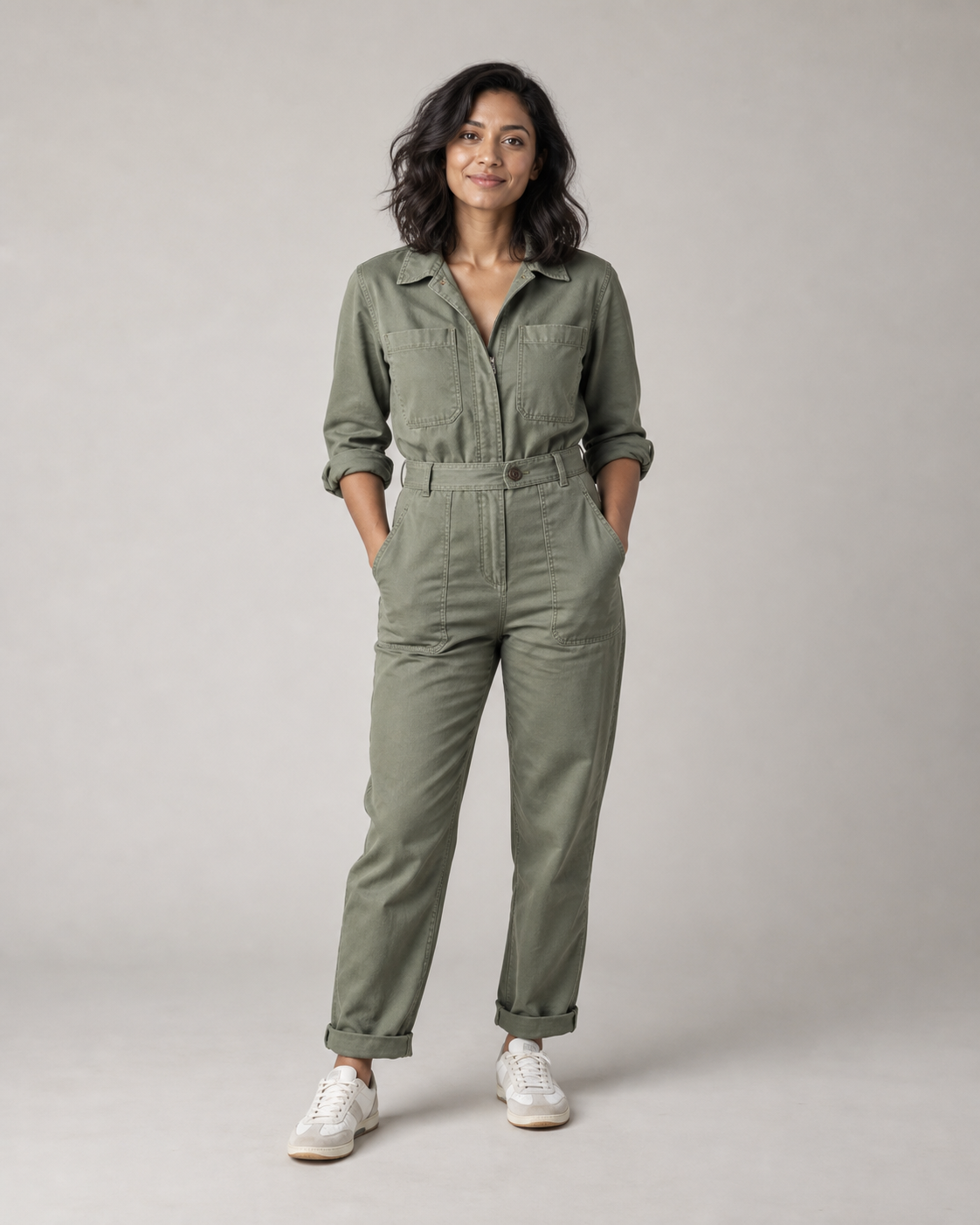 A fictional architect in a sage green jumpsuit standing in a photography studio
